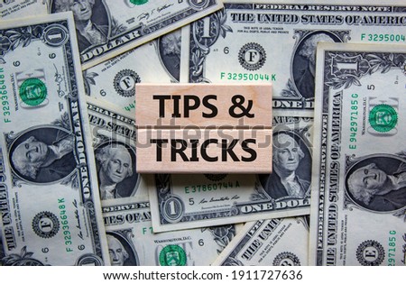 Tips and tricks symbol. Wooden blocks with words 'Tips and tricks'. Beautiful background from dollar bills. Business, tips and tricks concept. Copy space.