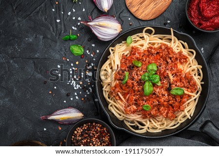 Culinary background with pasta and tomato sauce and fresh herbs on a black concrete background. The concept of cooking. Royalty-Free Stock Photo #1911750577