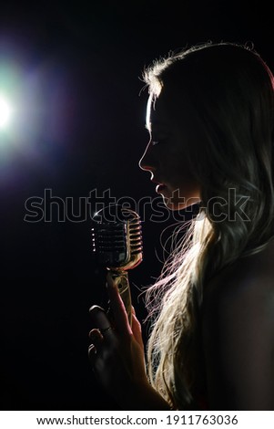 Silhouette of the singer with a microphone on a dark background