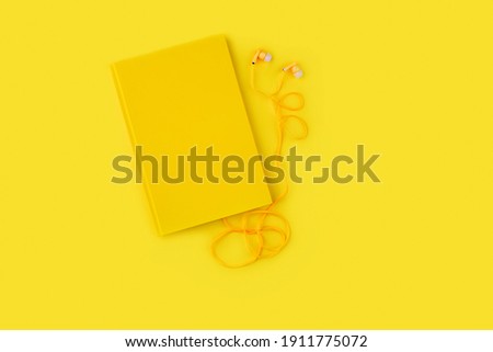 yellow note book and headphones on a yellow background. audiobook         