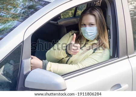 Female car driver wearing face mask showing like sign. Woman taxi driver encouraging to wear face mask for protection against corona virus epidemic. Covid-19 safety protection concept