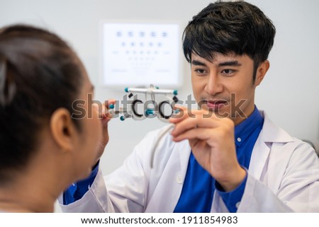 Selective focus at women face. While doctor using Optometry equipment and trial glasses frame  to examine eye visual system of elder patient women with professional machine and technic.