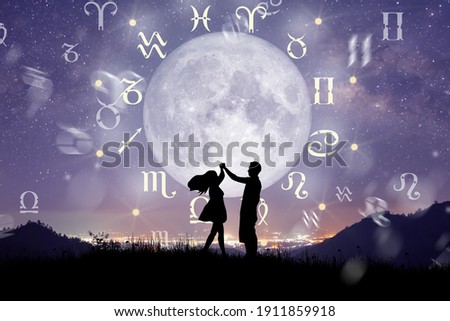 Astrological zodiac signs inside of horoscope circle. Couple singing and dancing over the zodiac wheel and milky way background. The power of the universe concept. Royalty-Free Stock Photo #1911859918