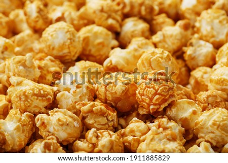 Caramel popcorn close-up as a background, full-screen texture. Admirable praise for watching movies, TV series, cartoons. Close-up, top view