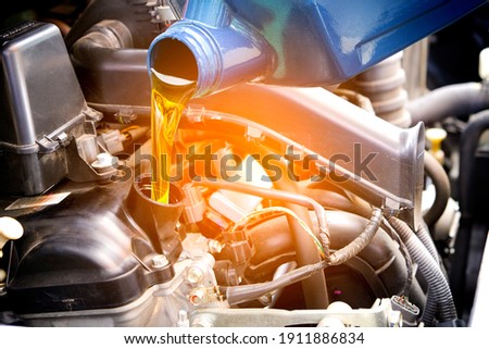 Refueling and pouring oil quality into the engine motor car Transmission and Maintenance Gear .Energy fuel concept. Royalty-Free Stock Photo #1911886834