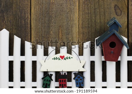 White picket fence with birdhouse and blank decorative sign