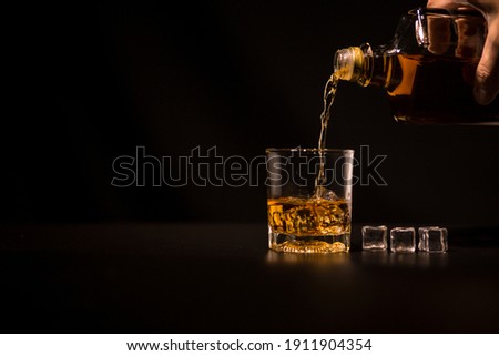 Closeup Barman pouring whiskey into glass Royalty-Free Stock Photo #1911904354