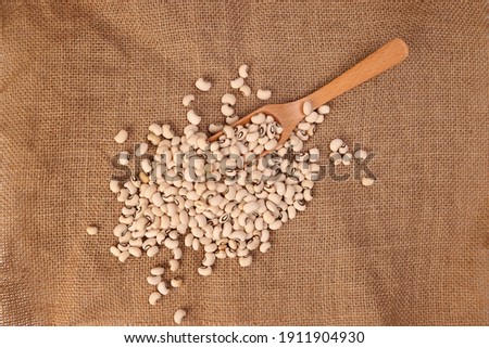 Blackeye beans in wooden scoop spoon jute yarn fabric background