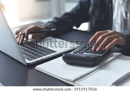 Close up of businesswoman or accountant using calculator to calculate calculate business data, working at office, accountancy document and laptop computer on office table, business and finance concept Royalty-Free Stock Photo #1911917056