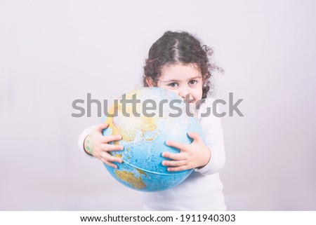 A closeup portrait curious child holding an earth globe map in his hand