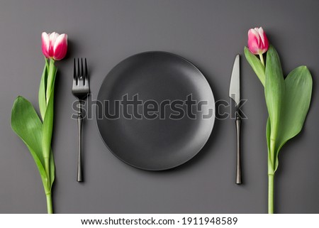 Festive creative black table setting with and tulip bouquet on dark background. Valentine's Day, Wedding Day, Birthday, Women's Day and Mother's Day. Flat lay Royalty-Free Stock Photo #1911948589