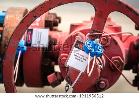 "Lock out tag out" sign is attached on the machine valve in oil and gas processing plant, using for safety equipment. Close-up and selective focus.