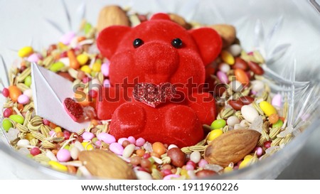 Red bear with shiny heart with love letter with treats in a bowl present or gift on valentines day or women birthday .
