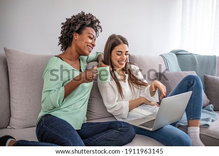 Photo series of two female teenage friends using social media for various purposes at home on the couch. Two happy friends watching comedy movie on laptop