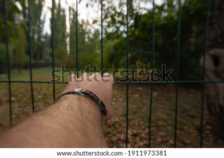 hand holding on to the bars of the fence