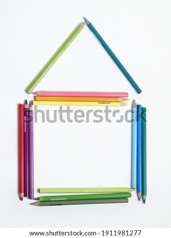 Colored pencils are laid out on a white background in the shape of a house.