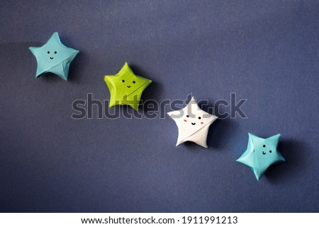 Four cute paper origami stars on blue paper background