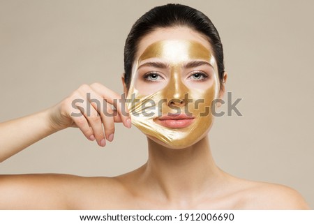 Woman peel off Gold Facial Mask. Collagen Golden Anti Aging Wrinkle Lifting Mask. Spa Beauty Treatment Royalty-Free Stock Photo #1912006690