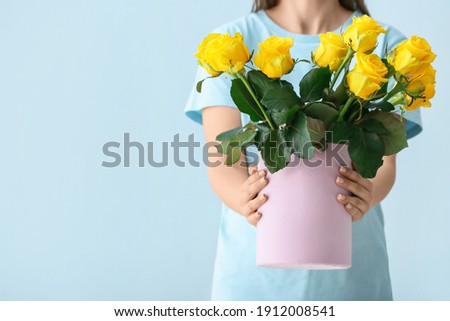 Woman with bouquet of beautiful yellow roses on color background