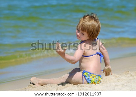 Cute girl in swimsuit playing on a sandy beach