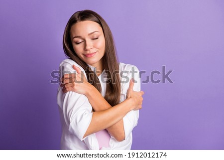 Photo of young lovely pretty dreamy cute sweet smiling girl embrace herself isolated on violet color background