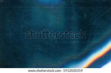 Dust scratches overlay. Old film effect. Blue distressed faded glass with smeared dirt stains colorful rainbow lens flare design. Royalty-Free Stock Photo #1912020319