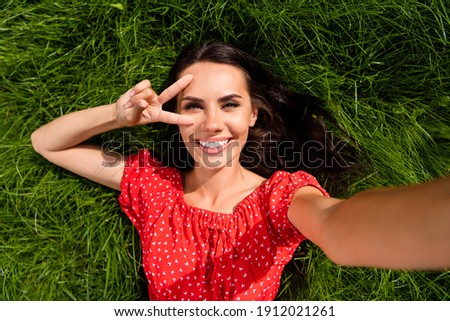 Top above high angle view of cheerful woman make selfie lie grass show v-sign in park outside outdoors