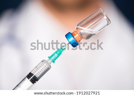 Concept of COVID-19 - Coronavirus disease - Doctor with syringe is preparing for injection. Royalty-Free Stock Photo #1912027921