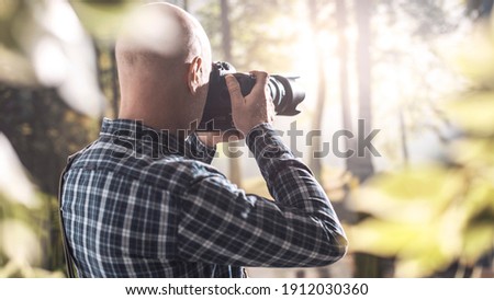 Professional wildlife photographer shooting in a forest with a digital camera