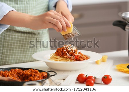 Woman cooking tasty pasta bolognese in kitchen, closeup Royalty-Free Stock Photo #1912041106