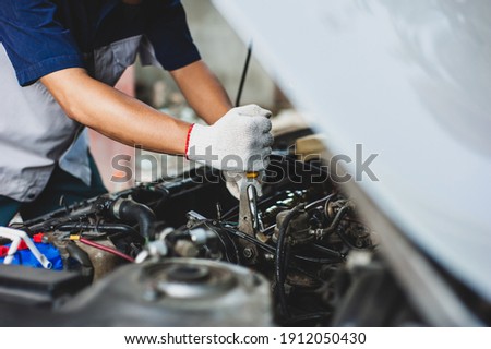 Mechanic uses a wrench to fix the car engine. Royalty-Free Stock Photo #1912050430