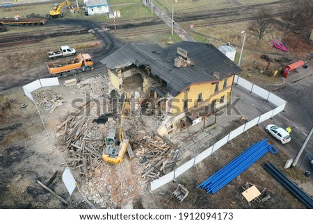 Yellow excavator destroys building. Heavy duty machine is demolishing a brick building. Demolition of the building . Demolition construction work aerial drone photo view
