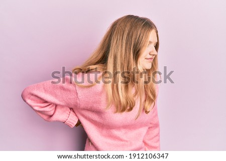 Beautiful young caucasian girl wearing casual clothes suffering of backache, touching back with hand, muscular pain 