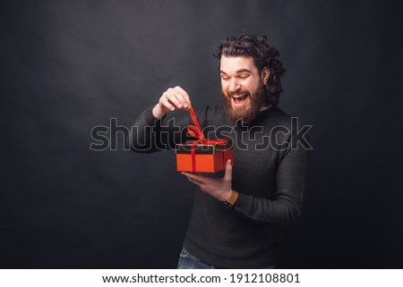 Amazed bearded handsome man opening a gift box.