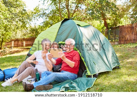 Group of happy seniors takes a selfie while camping in front of the tent in nature