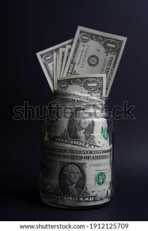 American dollars in the glass jar, you can save money. Easy ways to save real money. Black background. Bank image and photo.