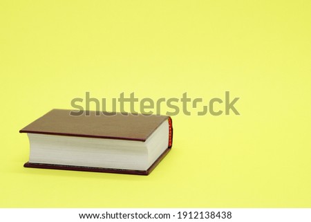 Thick old book on yellow background. Space for text. Concept: education, session, love of literature, reading, knowledge