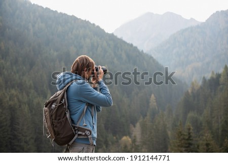 Man photographer taking photographs with digital camera in a mountains. Creative professional photographing. Travel, hobby and active lifestyle concept Royalty-Free Stock Photo #1912144771