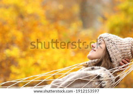 Side view portrait of a happy woman relaxing lying on a hammock in autumn in a forest Royalty-Free Stock Photo #1912153597