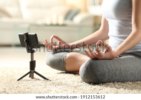 Close up of a female doing yoga watching online video tutorial on mobile phone at home