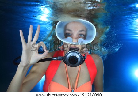 Happy female scuba diver show underwater signal 