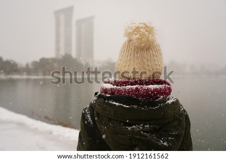
Woman in winter clothes during a snowfall. Photo from the back