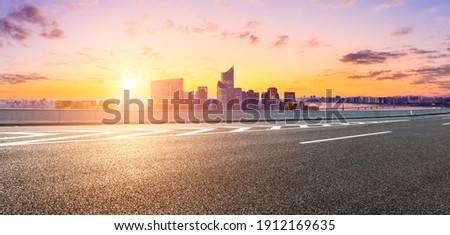 Asphalt road and modern city skyline with buildings in Hangzhou at sunset.