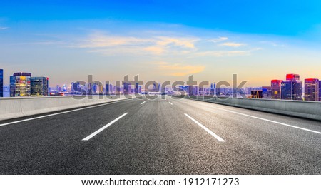 Asphalt road and modern city skyline with buildings in Hangzhou at night.