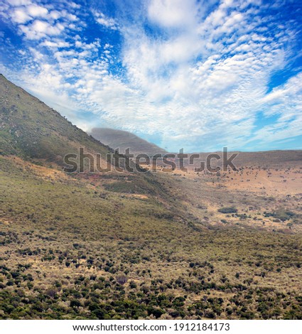 Kenyan valley with clouds in the sky and mountains in the background