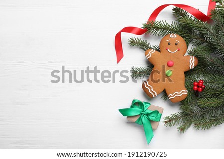 Flat lay composition with gingerbread man and Christmas decor on white wooden table, space for text