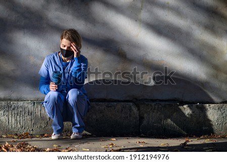 Worried woman caregiver or healthcare worker having a break outdoors, coronavirus concept.