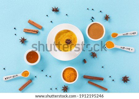 Turmeric golden milk latte with spices, cinnamon and honey on blue background. Top view, copy space. Detox, immune boosting, anti inflammatory healthy traditional indian drink.