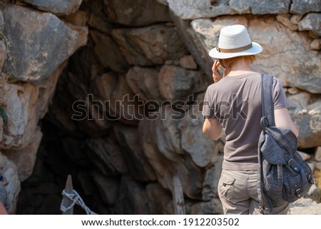 A tourist girl examines the sights on the territory of the archaeological complex in Mycenae at noon