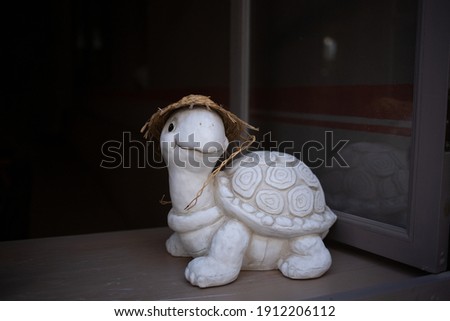 A turtle made out of plaster of paris with a hat